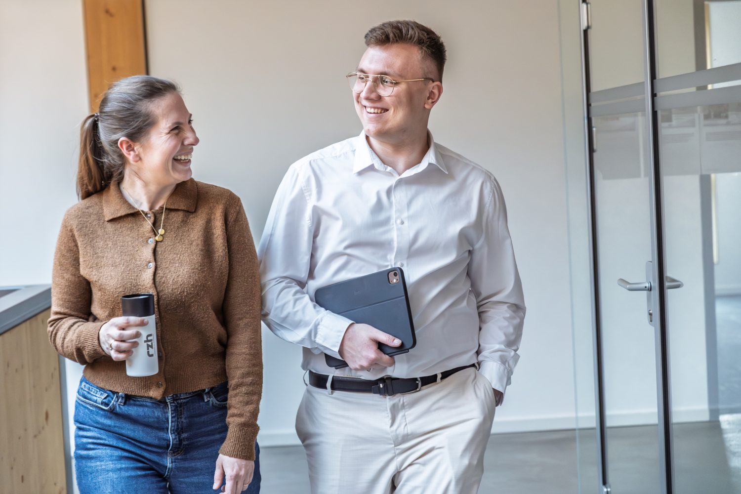 Ein Mann und eine Frau laufen in einem Bürogebäude.