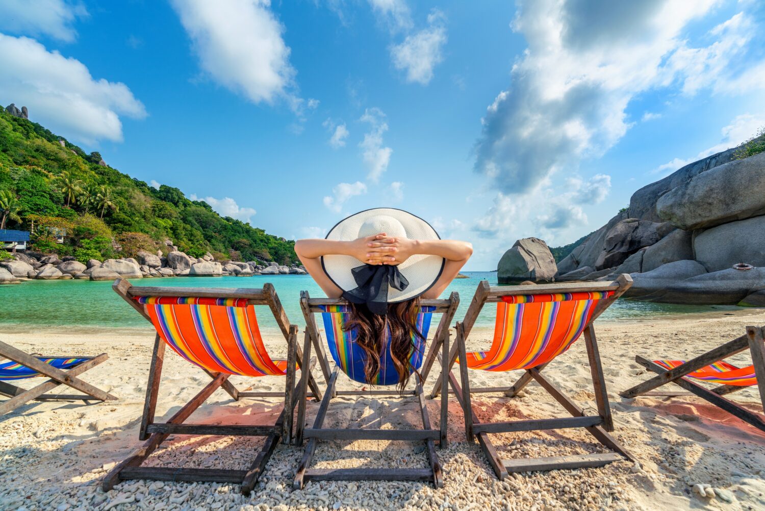 Frau liegt am Strand im Stuhl, vor ihr das tropische Meer
